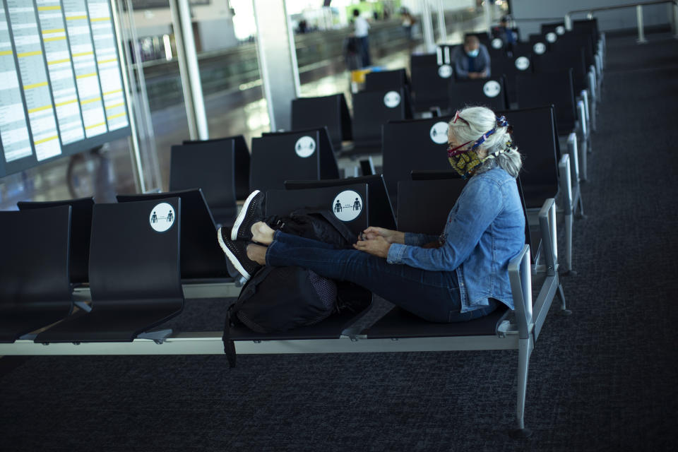 A passenger, wearing a face mask to protect against the spread of coronavirus, sits before boarding her flight at the Zaventem international airport during the partial lifting of coronavirus COVID-19 lockdown regulations in Brussels, Monday, June 15, 2020. Borders opened up across Europe on Monday after three months of coronavirus closures that began chaotically in March. (AP Photo/Francisco Seco)