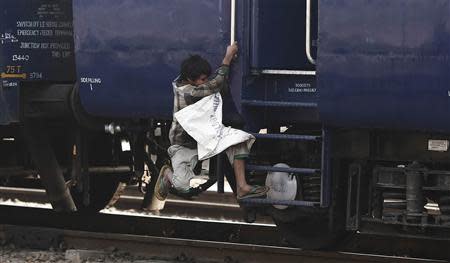 A ragpicker boy jumps onto a moving train in search of plastic bottles for reselling, at a railway station in New Delhi February 18, 2014. REUTERS/Adnan Abidi