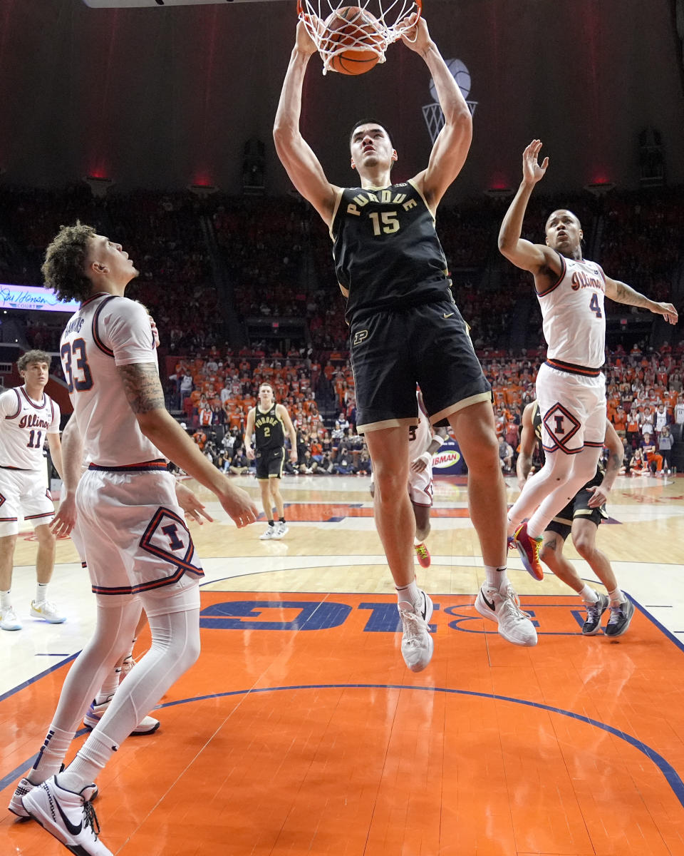 Purdue's Zach Edey (15) dunks between Illinois' Coleman Hawkins (33) and Justin Harmon during the first half of an NCAA college basketball game Tuesday, March 5, 2024, in Champaign, Ill. (AP Photo/Charles Rex Arbogast)