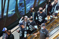 Seattle Kraken fans take an escalator down and past a giant video screen displaying an ocean theme for their first look at Climate Pledge Arena, Saturday, Oct. 23, 2021, in Seattle. The team was set to play its inaugural home match as the newest NHL team against the Vancouver Canucks later Saturday. (AP Photo/Elaine Thompson)