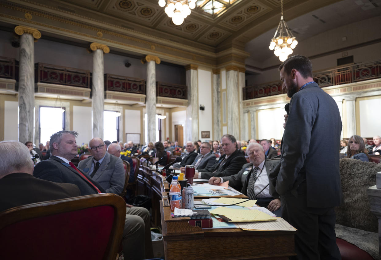 Rep. Casey Knudsen speaks on the House floor, surrounded by a full complement of Montana lawmakers.