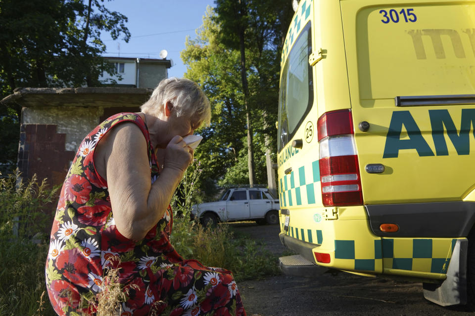 A woman cries after the body of her husband, who was killed in a yard of an apartment building during shelling, was loaded into an ambulance in Kharkiv, Ukraine, Monday, June 27, 2022. (AP Photo/Andrii Marienko)