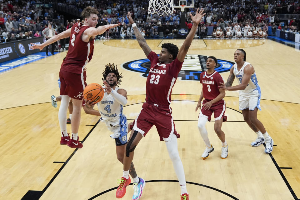 North Carolina guard RJ Davis (4) drives to the basket between Alabama forward Grant Nelson (2) and forward Nick Pringle (23) during the second half of a Sweet 16 college basketball game in the NCAA tournament Thursday, March 28, 2024, in Los Angeles. (AP Photo/Ashley Landis)