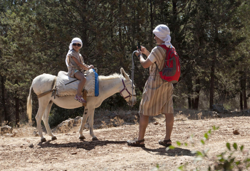 American tourist Peter Scherr uses a smartphone to send a photograph of his daughter using a Wi-Fi router placed on a donkey Kfar Kedem, a biblical reenactment park in the village of Hoshaya in the Galilee, northern Israel, Wednesday, Aug. 22, 2012. Visitors riding donkeys through the Old Testament landscape can now also surf the web while being transported across the land of the Bible. Organizers are hoping to connect the younger generation to ancient Galillee life while allowing them to like, share, tweet and snap it instantly to their friends. (AP Photo/Ariel Schalit)