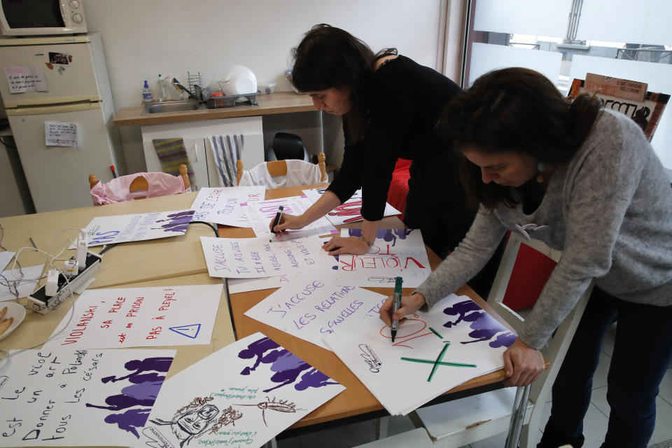Celine Piques, right, and Alix Chazeaux-Guibert, from women's activist group "Osons le Feminisme" prepare posters in Paris, Thursday, Feb.27, 2020. French women's rights activists prepare to protest Friday against multiple nominations for Roman Polanski at the Cesar Awards ceremony, France's equivalent of the Oscars. This year's Cesars have been shaken by boycott calls since the nominations for Polanski's "An Officer and a Spy," because a French woman recently accused Polanski of raping her in the 1970s, which he denies. (AP Photo/Francois Mori)