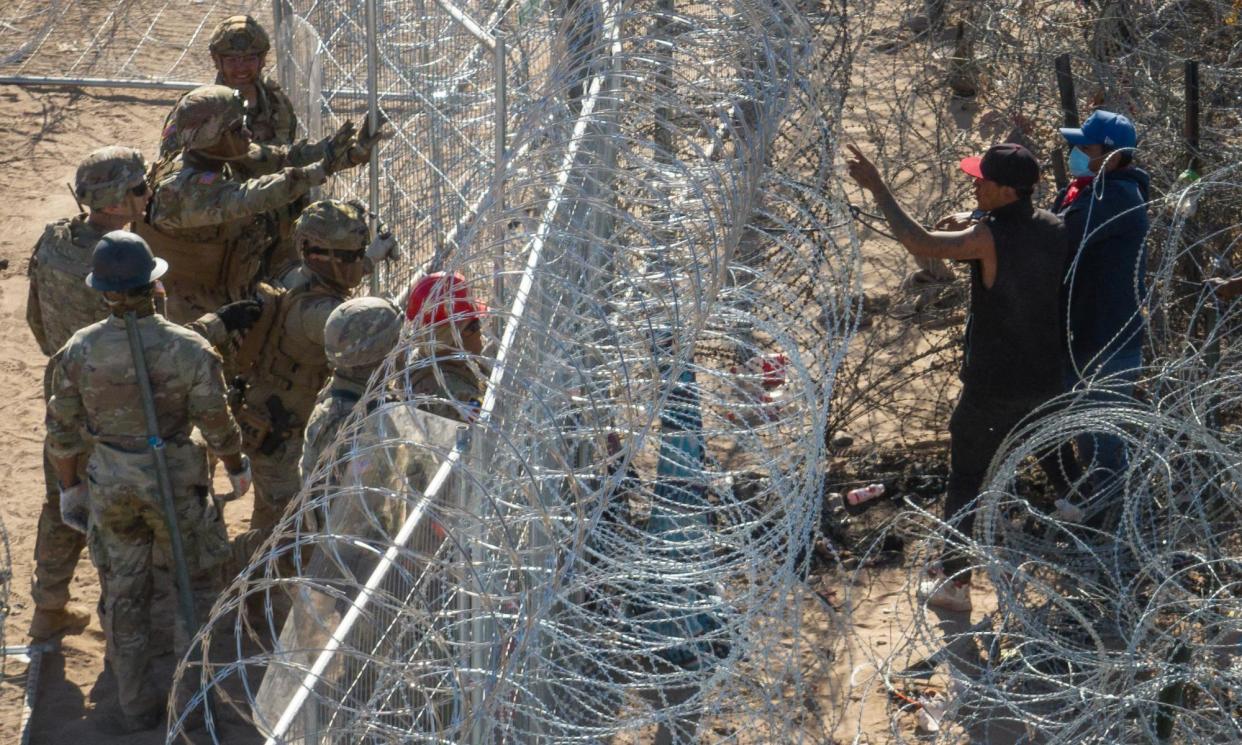 <span>Migrants and national guard troops at the razor-wire fence.</span><span>Photograph: Adrees Latif/Reuters</span>