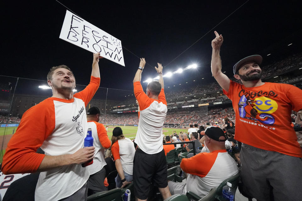 Kevin Tehansky, left, holds a sign in support of broadcaster Kevin Brown while he and a group of friends engage in "The Wave" during the eighth inning of a baseball game between the Baltimore Orioles and the Houston Astros, Tuesday, Aug. 8, 2023, in Baltimore. The Astros won 7-6. The Orioles indicated that Brown would be back on the air soon after reports that his recent absence was because he mentioned that the team had already won as many games at Tampa Bay this year as it did over the previous three seasons. Announcers such as Michael Kay of the YES Network came to Brown's defense. The Athletic, citing unidentified sources, reported that Brown was taken off the air over his comments on a MASN-TV broadcast July 23. A team official says the Orioles don't comment on personnel matters but were looking forward to having Brown back soon. (AP Photo/Julio Cortez)