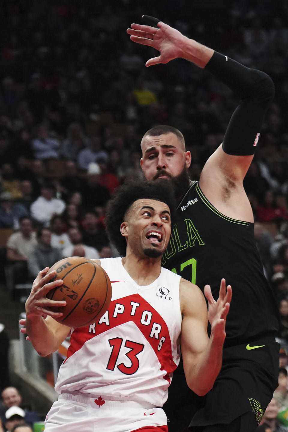 Toronto Raptors forward Jordan Nwora (13) drives around New Orleans Pelicans center Jonas Valanciunas (17) during the second half of an NBA basketball game Tuesday, March 5, 2024, in Toronto. (Nathan Denette/The Canadian Press via AP)