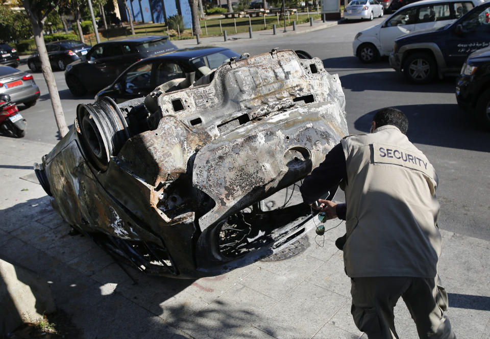 A private security worker takes pictures of a burned car that was set on fire early Tuesday by supporters of the Shiite Hezbollah and Amal Movement groups, in Beirut, Lebanon, Tuesday, Dec. 17, 2019. Supporters of Lebanon's two main Shiite groups Hezbollah and Amal clashed with security forces and set fires to cars in the capital early Tuesday, apparently angered by a video circulating online that showed a man insulting Shiite figures.(AP Photo/Hussein Malla)