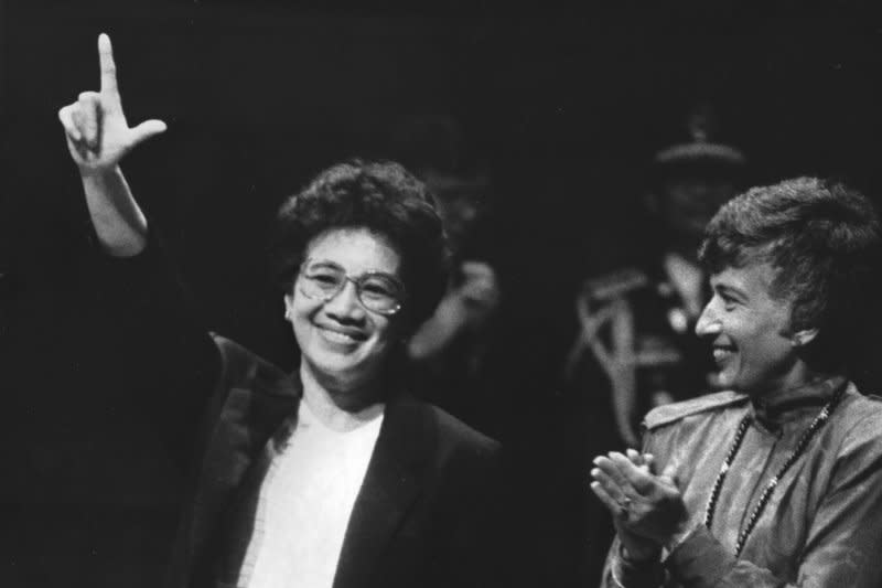The late Philippine President, Corazon Aquino, gives the Philippine revolution sign to a standing ovation at Memorial Hall at Harvard University after delivering an address on September 20, 1986. Matina Horner, President of Radcliffe College (R) looks on. File photo by George Riley/UPI