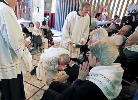 Pope Francis kisses a foot of a disabled person at the S. Maria della Provvidenza church in Rome, during a Holy Thursday celebration, in this April 17, 2014 file photo. REUTERS/Tony Gentile/Files