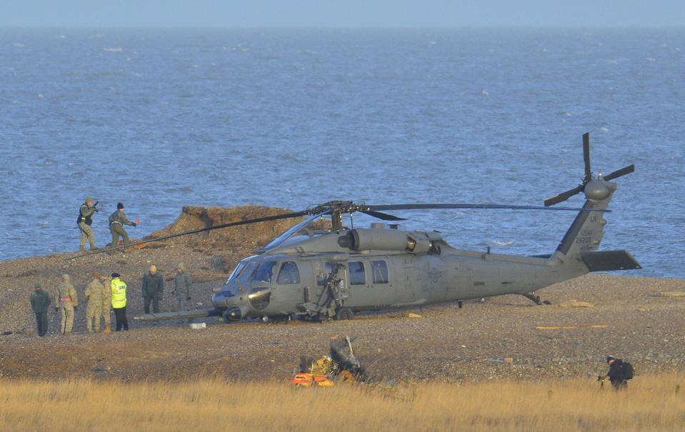 A Pave Hawk helicopter, military personnel and emergency services attend the scene of a helicopter crash on the coast near the village of Cley in Norfolk, eastern England
