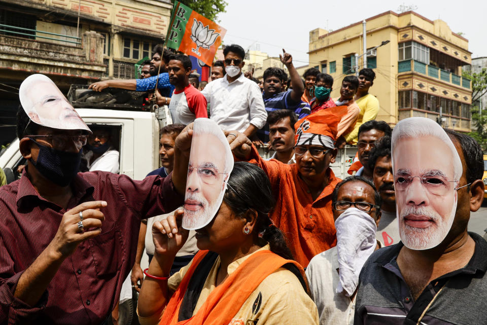 FILE - In this March 20, 2021, file photo, supporters of Bharatiya Janata Party wearing masks bearing the likeness of Prime Minister Narendra Modi participate in a campaign rally ahead of elections in West Bengal state in Kolkata, India. Despite clear signs that India was being swamped by another surge of coronavirus infections, Modi refused to cancel the rallies, a major Hindu festival and cricket matches with spectators. The burgeoning crisis has badly dented Modi’s carefully cultivated image as an able technocrat. (AP Photo/Bikas Das, File)