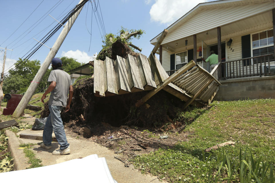 A Tupelo resident walks by a home on North Green Street on Monday, May 3, 2021 that had a tree fall and it roots tear out the decking and stairway to the home after a tornado passed through the city Sunday night. (Adam Robison/The Northeast Mississippi Daily Journal via AP)