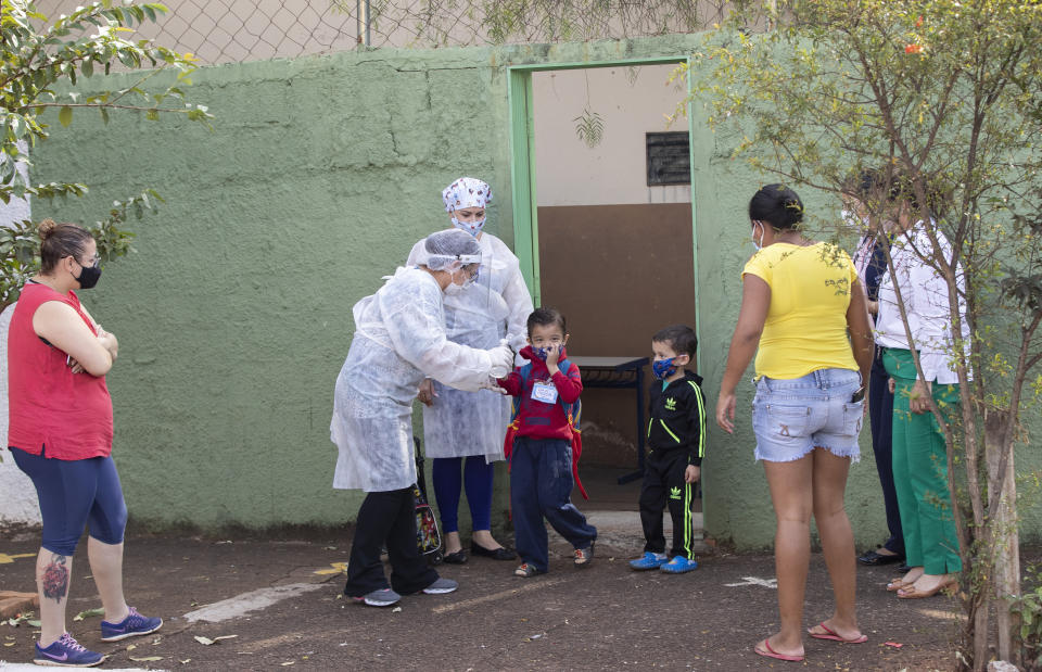 Parents pick up their children from a public school in Serrana, Sao Paulo state, Brazil, Friday, May 28, 2021. Brazil's Butantan Institute has finished a mass vaccination of the city's entire adult population with doses of Sinovac, to test the new coronavirus' behavior in response to the vaccine. (AP Photo/Andre Penner)