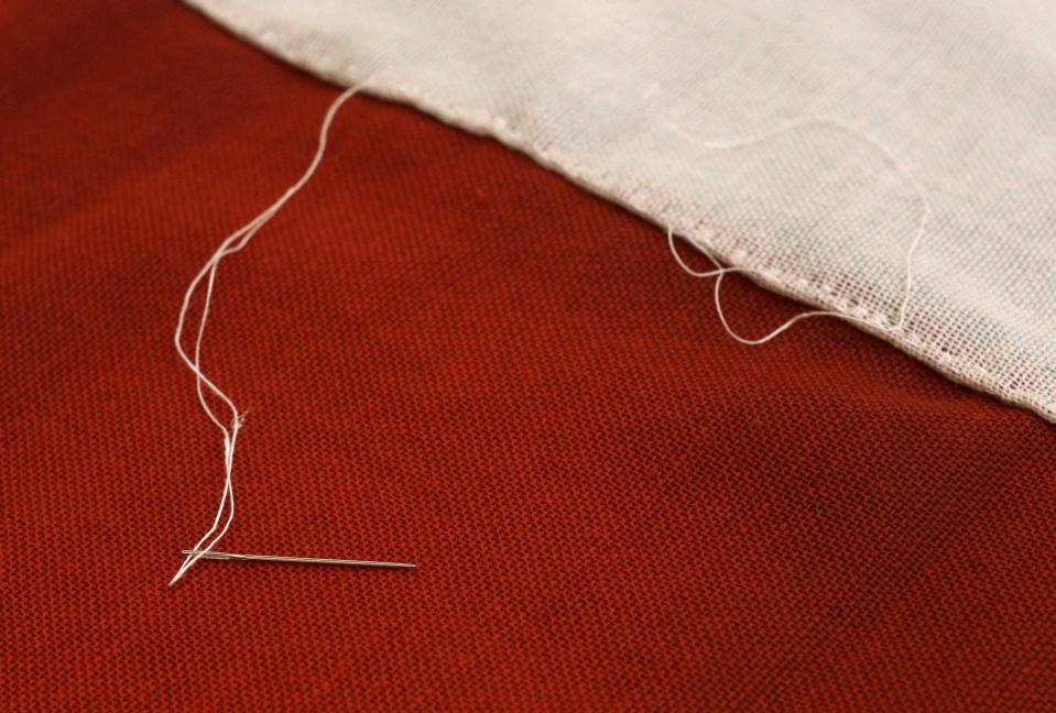 In this July 22, 2013 picture, a thread and needle rest on a replica of the star-spangled banner in Baltimore. It was 200 years ago this summer that a Baltimore flag-maker stitched the flag that inspired America’s national anthem. Now, hundreds of people are helping to recreate the star-spangled banner. The project began July 4 in Baltimore, and it is expected to take volunteers six weeks to hand sew the estimated 150,000 stitches in the famous flag. When finished, it will be about a quarter of the size of a basketball court. (AP Photo/Patrick Semansky)