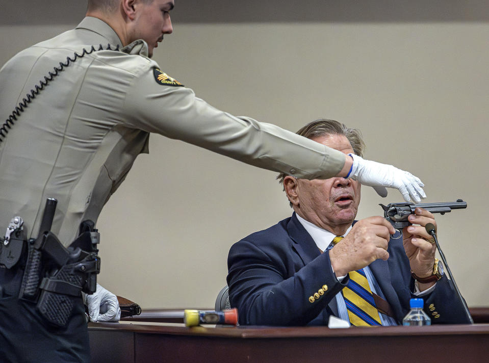Santa Fe County Sheriffs Deputy Levi Abeyta, left, intervenes as a firearms expert for the defense, Frank Koucky III, points a replica gun in the direction of Judge Mary Marlowe Sommer while demonstrating how to remove the cylinder from a gun like the one used in the "Rust" shooting as Koucky testifies in the involuntary manslaughter trial of movie armorer Hannah Gutierrez-Reed, Tuesday, March 5, 2024, at the First Judicial District Courthouse in Santa Fe, N.M. (Jim Weber/Santa Fe New Mexican via AP, Pool)