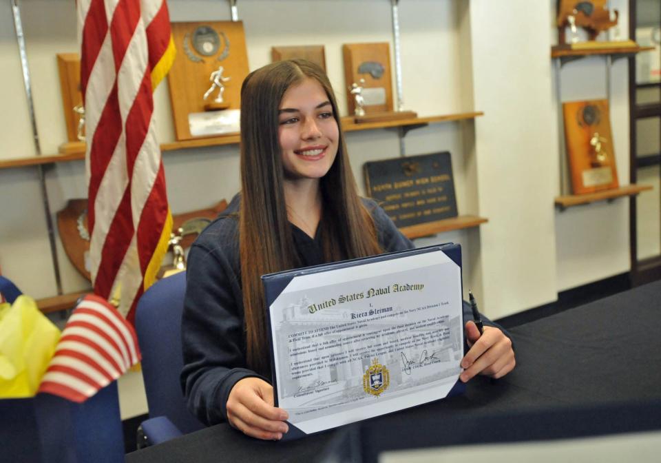 North Quincy High School senior and student-athlete Kiera Sleiman proudly shows her acceptance certificate to the United States Naval Academy during a signing ceremony at North Quincy High School on Friday, April 29, 2022.