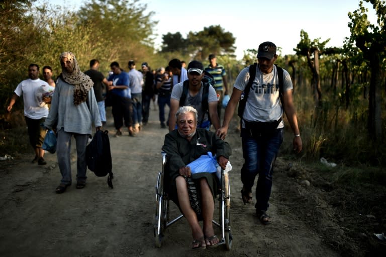 Abu Mohammad, a 74-years-old Syrian migrant, is helped by relatives after crossing the border from Greece to Macedonia, near the Greek village of Gevgelija, August 29, 2015