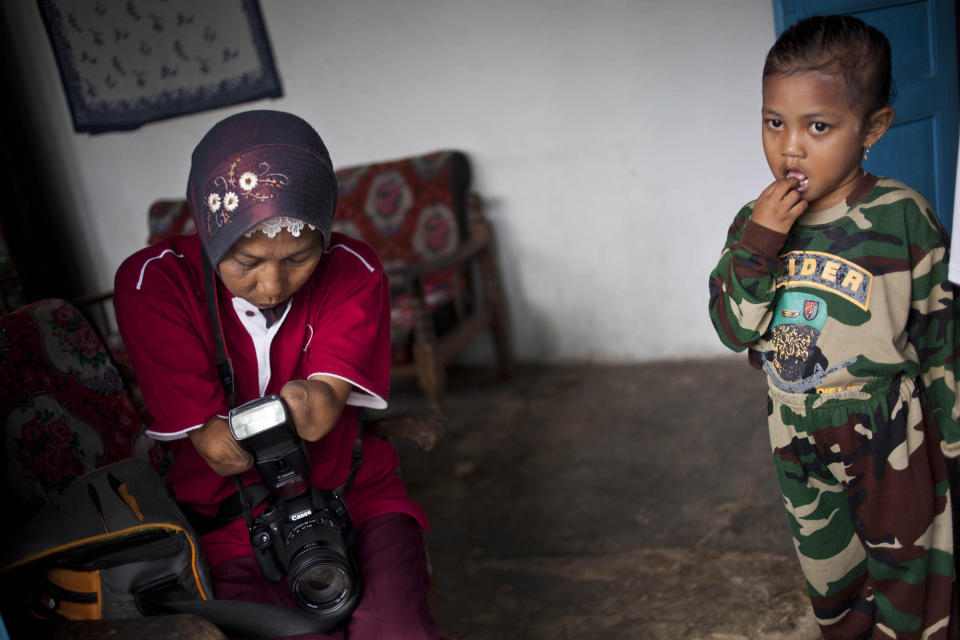 PURWOREJO, INDONESIA - MARCH 14: Armless professional photographer Rusidah, 44, prepares camera before taking a customer's portrait on March 14, 2012 in Purworejo, Indonesia. Rusidah shoots weddings and parties and has a small studio at home in the village of Botorejo, Bayan District, Purworejo, Central Java where her husband and son also reside. She has been in the photography business for nearly 20 years. (Photo by Ulet Ifansasti/Getty Images)