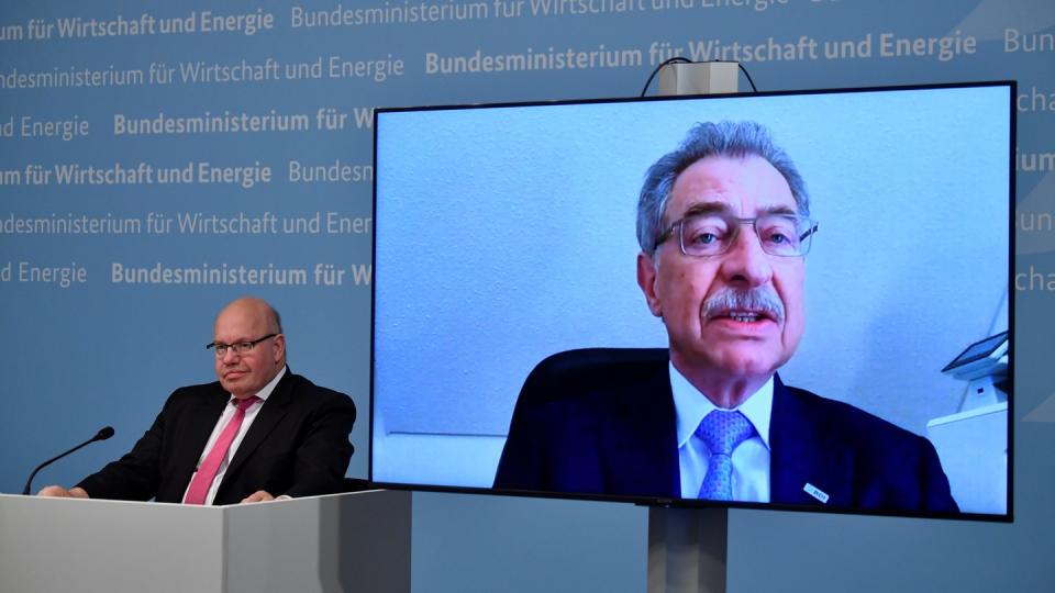 Bundeswirtschaftsminister Peter Altmaier (l) sitzt neben einer Leinwand, auf der BDI-Präsident Dieter Kempf zu sehen ist.