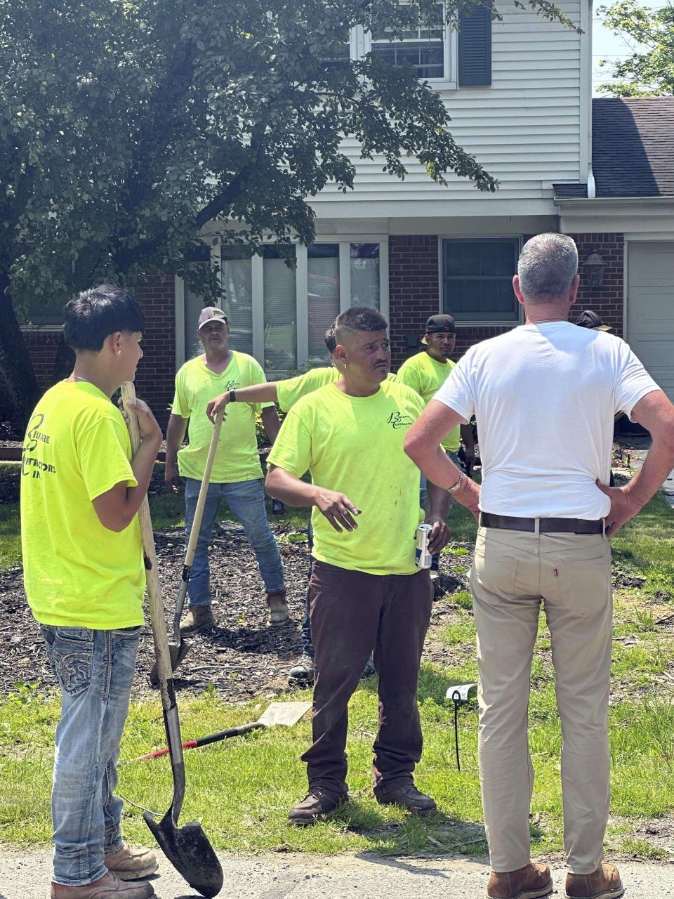 Jose Orozco, center, and other Bidigare Contractors employees work Monday, June 17, 2024, on a water main project in Farmington Hills, Mich., a suburb of Detroit. Orozco said workers drink lots of water and take frequent breaks when faced with doing their jobs in extreme heat. (AP Photo/Corey Williams)