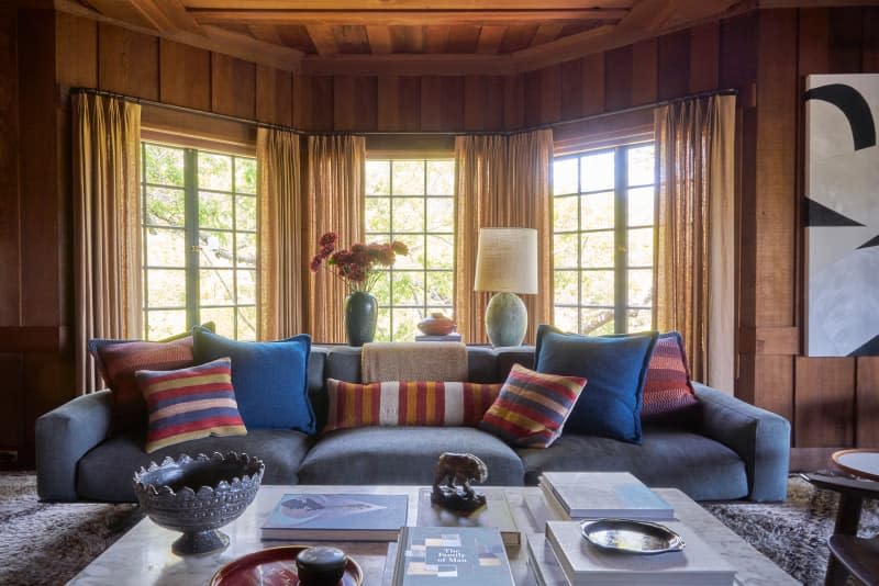 Decorative pillows top blue sofa in newly renovated wood panel living room.