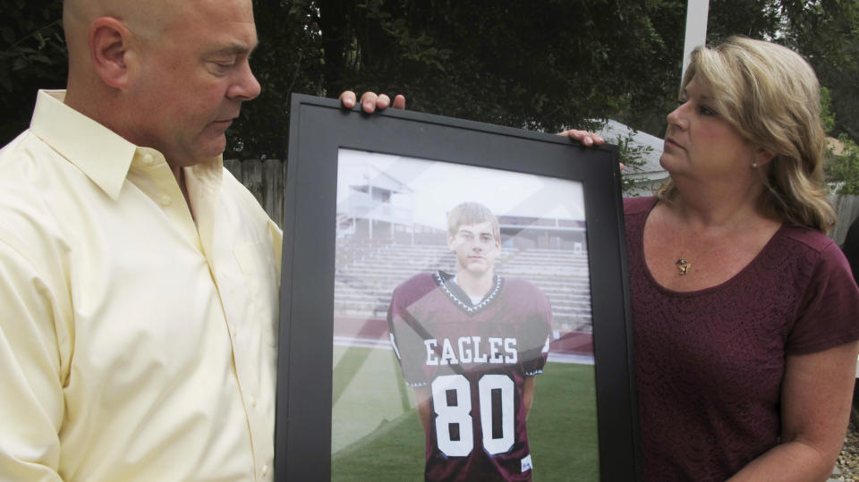 FILE - In this Sept. 25, 2014 file photo, Brian and Kathy Haugen hold an undated photo of their son Taylor Haugen, at their home in Niceville, Fla. New York Jets tight end Jordan Leggett has extra motivation for the Jets to score this season. The second-year tight end is currently running a campaign called "Touchdowns for Taylor," set up in memory of Taylor Haugen, a 15-year-old Florida high school wide receiver who died 10 years ago from an injury to his abdominal area on the football field. Along with Taylor Haugen's parents, Leggett is pushing for increased awareness and education for safety in youth football. (AP Photo/Melissa Nelson-Gabriel, File)