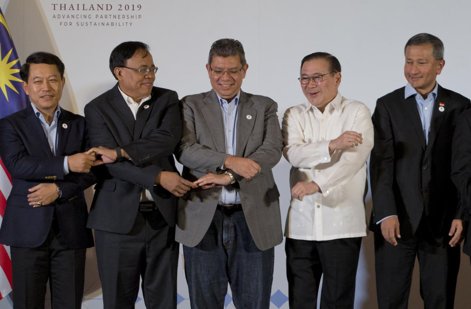 Foreign ministers of the Association of Southeast Asian Nations (ASEAN) cross hands in preparation for ASEAN style group photo as Singapore Foreign Minister Vivian Balakrishnan, right, watches during the ASEAN Foreign Ministers' retreat in Chiang Mai, Thailand,Friday, Jan. 18, 2019. The ministers are, from left, Laos' Saleumxay Kommasith, Myanmar's Kyaw Tin, Malaysia's Saifuddin Abdullah, Philippines Teodoro Locsin Jr.. (AP Photo/Gemunu Amarasinghe)