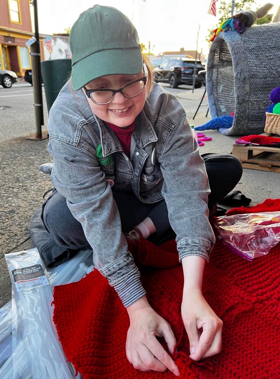 Volunteer Keely Serri works on yarn art on Sixth Street NW in downtown Canton. Yarn art is being installed on poles and buildings in the Sixth Street and Court Avenue NW area. The art installation will be up until September.