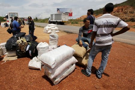 People stand next to bags filled with staple items while they wait for transportation in Santa Elena de Uairen, Venezuela August 3, 2016. REUTERS/William Urdaneta