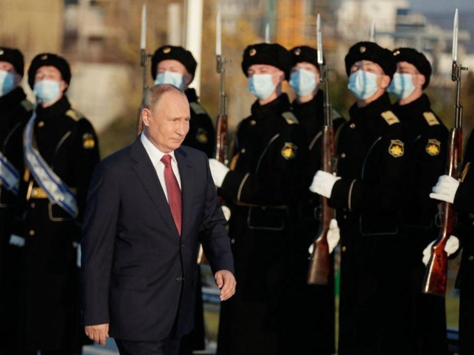 Russian President Vladimir Putin walks past military personnel during a ceremonial event.