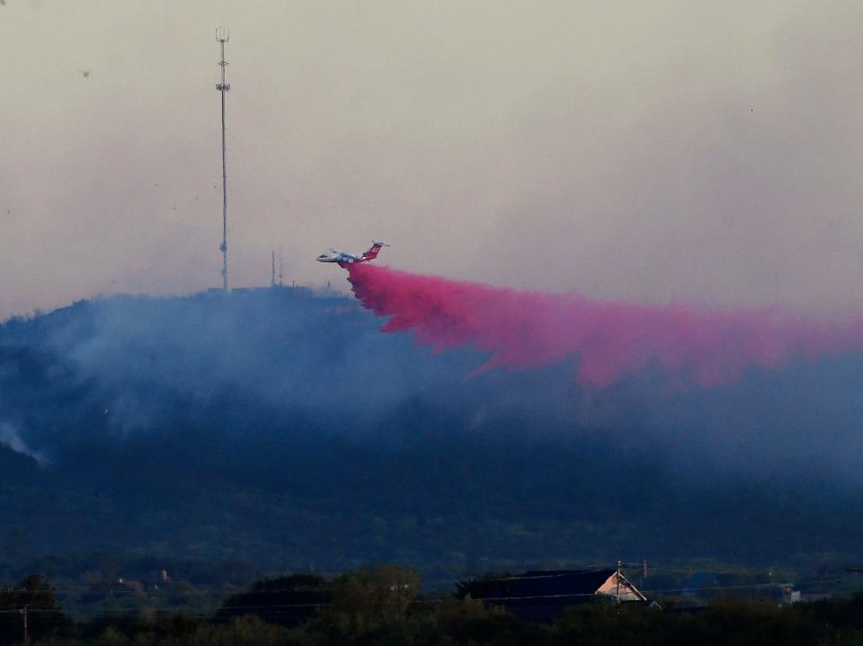An air tanker drops fire retardant over smoldering areas as the Hill Top Fire winds down Friday evening.