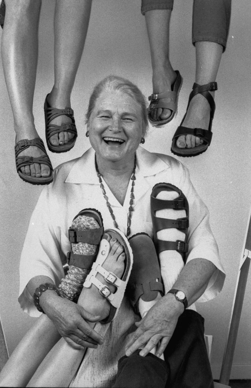 Margot Fraser, importer of Birkenstock Footprint Sandals, posing amidst the dangling feet of four people sporting the many varied styles of this cloddish sandal, at her distribution center.   (Photo by Kim Komenich/Getty Images)