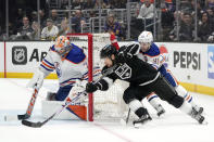 Los Angeles Kings right wing Viktor Arvidsson, center, tries to get a shot past Edmonton Oilers goaltender Stuart Skinner, left, as center Ryan Nugent-Hopkins defends during the second period in Game 4 of an NHL hockey Stanley Cup first-round playoff series Sunday, April 28, 2024, in Los Angeles. (AP Photo/Mark J. Terrill)