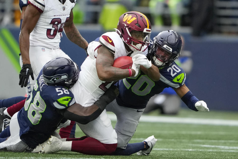 Washington Commanders running back Antonio Gibson (24) is tackled by Seattle Seahawks linebacker Derick Hall (58) and Seattle Seahawks safety Julian Love (20) in the first half of an NFL football game in Seattle, Sunday, Nov. 12, 2023. (AP Photo/Lindsey Wasson)