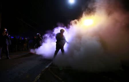 A police officer extinguishes a police car set on fire by protesters in Ferguson, Missouri, November 25, 2014. REUTERS/Adrees Latif