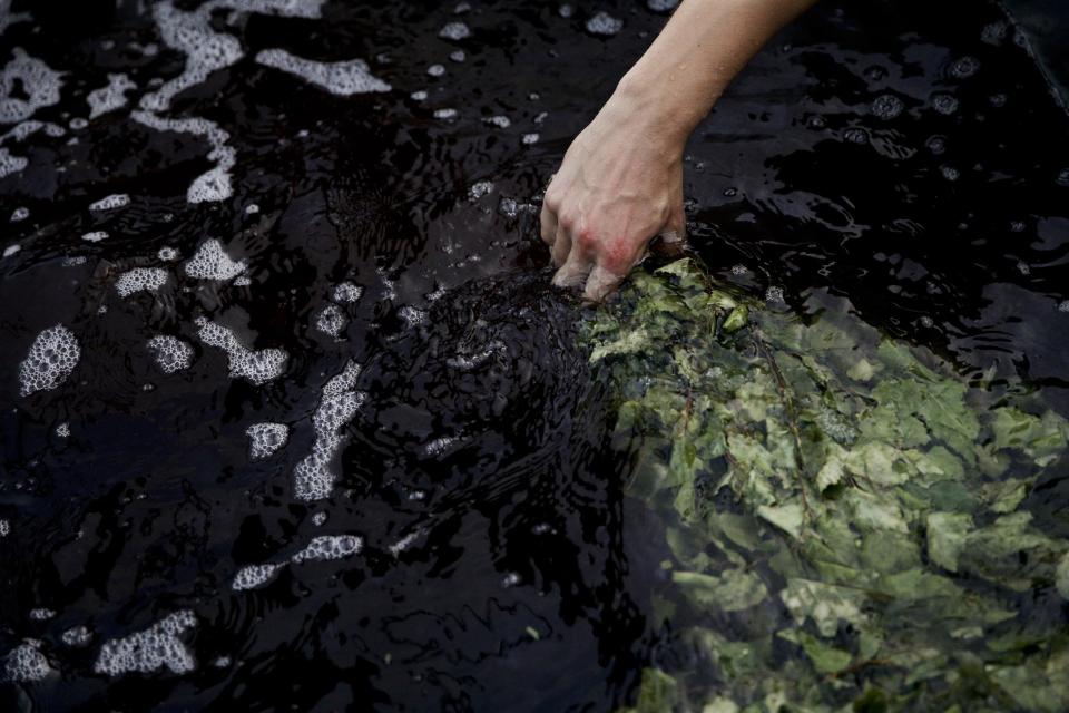 Bathhouse worker Roman Korotkov dips herbs in a large pot of hot bathwater at the British Banya bathhouse, Saturday, Feb. 15, 2014, in Krasnaya Polyana, Russia. The banya is an institution in Russia, where bathhouse traditions date back for centuries. (AP Photo/Jae C. Hong)