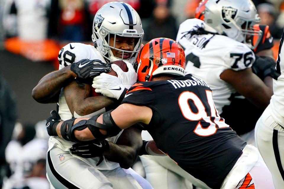 Cincinnati Bengals defensive end Sam Hubbard (94) and Cincinnati Bengals linebacker Germaine Pratt (57) tackle Las Vegas Raiders running back Josh Jacobs (28) in the first quarter during an NFL AFC wild-card playoff game, Saturday, Jan. 15, 2022, at Paul Brown Stadium in Cincinnati.