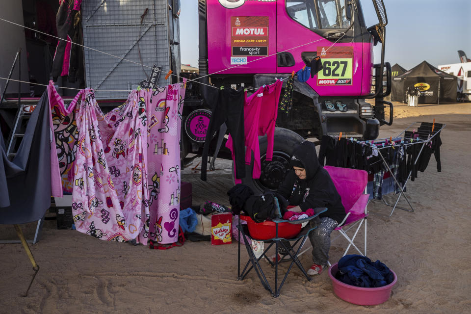 A team member of driver Camelia Liparoti, of Italy, and co-driver Annett Fischer, of Germany, does the laundry after stage eight of the Dakar Rally in Wadi Al Dawasir, Saudi Arabia, on Jan. 13, 2020. (AP Photo/Bernat Armangue)