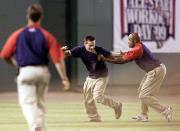 A fan tries to elude security guards after he ran on the field while Ken Griffey Jr. (not seen) of the Seattle Mariners was participating in the second round of the Home-Run Derby during the 70th Baseball All-Star Week 12 July, 1999, at Fenway Park in Boston. The All-Star will be played 13 July between the American and National Leagues. (Photo by Stephen Jaffe/AFP/Getty Images)