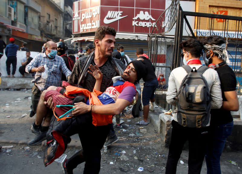 FILE PHOTO: An Iraqi demonstrator carries a wounded man during the ongoing anti-government protests, in Baghdad