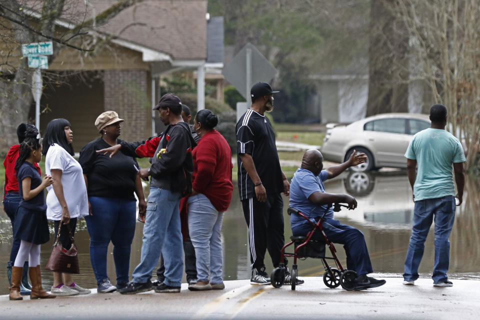 Area residents observe the swirling Pearl River floodwaters drain from North Canton Club Circle in Jackson, Miss., Tuesday, Feb. 18, 2020. Officials have limited entry to the flooded neighborhoods as they have warned residents about the contamination of the receding waters and the swift currents. (AP Photo/Rogelio V. Solis)