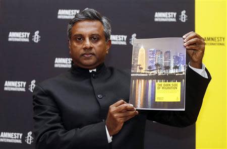 Amnesty International Secretary General Salil Shetty holds up a report titled "The Dark Side of Migration: Spotlight on Qatar’s construction sector ahead of the World Cup", during a news conference in Doha November 17, 2013. REUTERS/Mohammed Dabbous