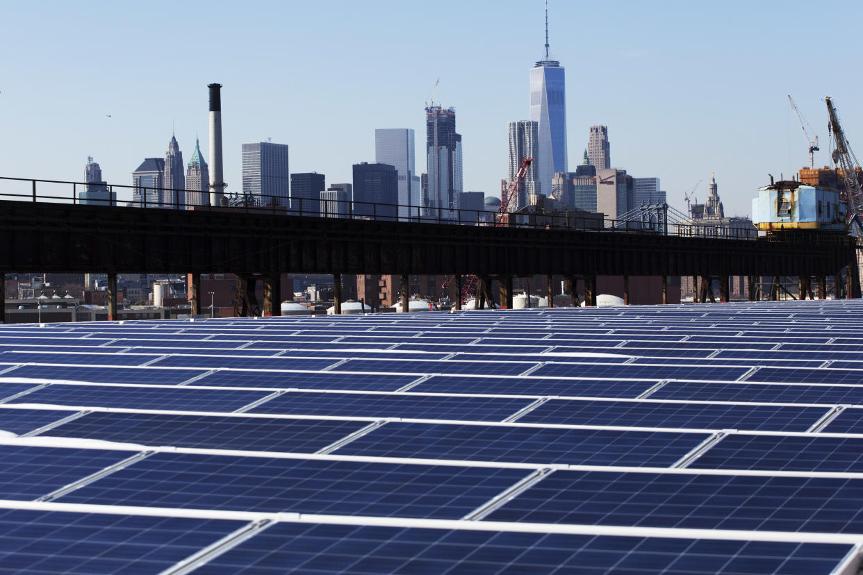 The Manhattan skyline peers over a rooftop covered with solar panels at the Brooklyn Navy Yard in New York. (Photo: ASSOCIATED PRESS)