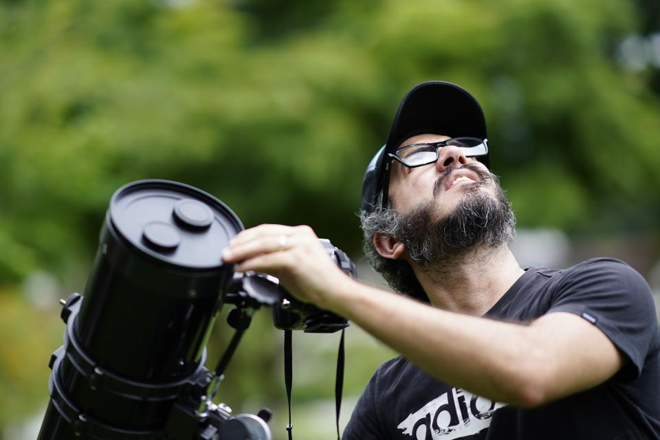 Carlos Guzman, 37, from Venezuela sets up a telescope as people gather to see the "ring of fire" solar eclipse in Panama City, Saturday, Oct. 14, 2023. Due clouds and rains in Panama City the eclipse was not visible. (AP Photo/Arnulfo Franco)