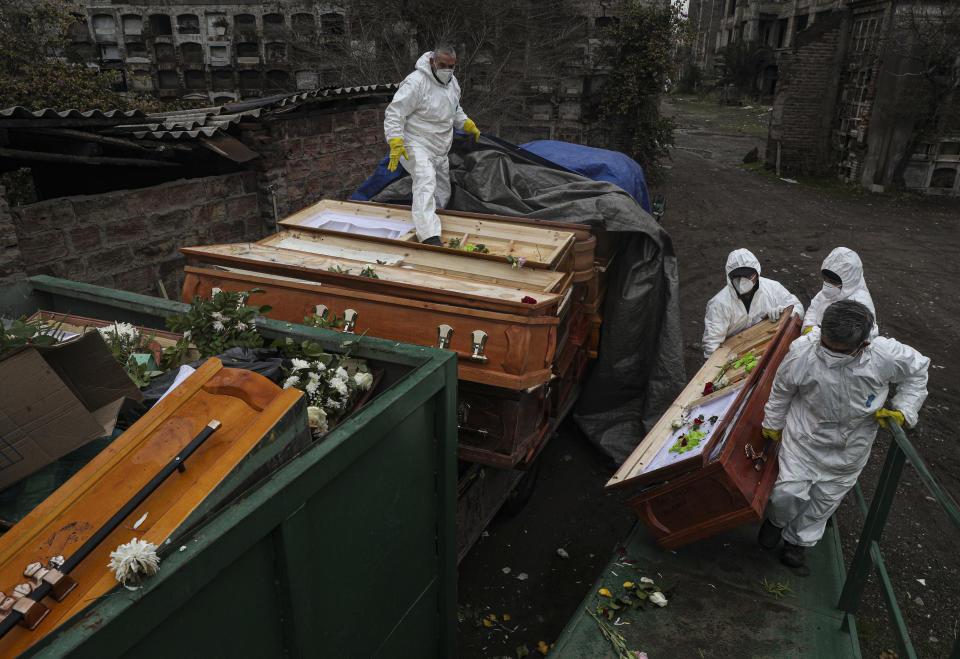 Workers collect and stack the coffins of people that have been recently cremated amid the new coronavirus pandemic at La Recoleta cemetery, in Santiago, Chile, Monday, July 6, 2020. The coffins are collected and destroyed by a company specializing in organic waste. (AP Photo/Esteban Felix)