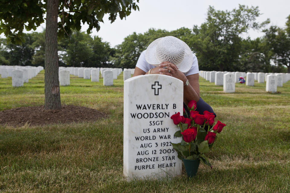 In this undated photo provided by Linda Hervieux, Joann Woodson kneels at the gravesite of her husband Cpl. Waverly B. Woodson Jr. at Arlington National Cemetery in Arlington, Va. Members of Congress on Tuesday, Sept. 8, 2020 said Woodson Jr., a Black army medic who saved dozens of wounded troops on the beaches of Normandy on D-Day despite being severely wounded himself, deserves the Medal of Honor, as they announced legislation to posthumously award it to him. (Linda Hervieux via AP, File)