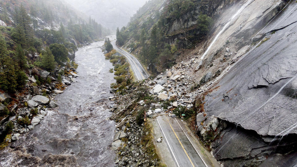 FILE- Rocks and vegetation cover Highway 70 following a landslide in the Dixie Fire zone on Sunday, Oct. 24, 2021, in Plumas County, Calif. Heavy rains blanketing Northern California created slide and flood hazards in land scorched during last summer's wildfires. Wildfires, floods and soaring temperatures have made climate change real to many Americans. Yet a sizeable number continue to dismiss the scientific consensus that human activity is to blame. (AP Photo/Noah Berger, File)