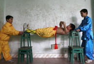 A student (C), with the help of his schoolmates, carries out strength practice at a Wushu school in Suining, in southwest China's Sichuan province December 14, 2006. CHINA OUT REUTERS/Stringer